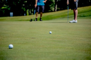 A ground view of a golf ball rolling toward the cup on a putting green