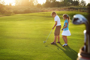 Kids at a golf course holding golf clubs