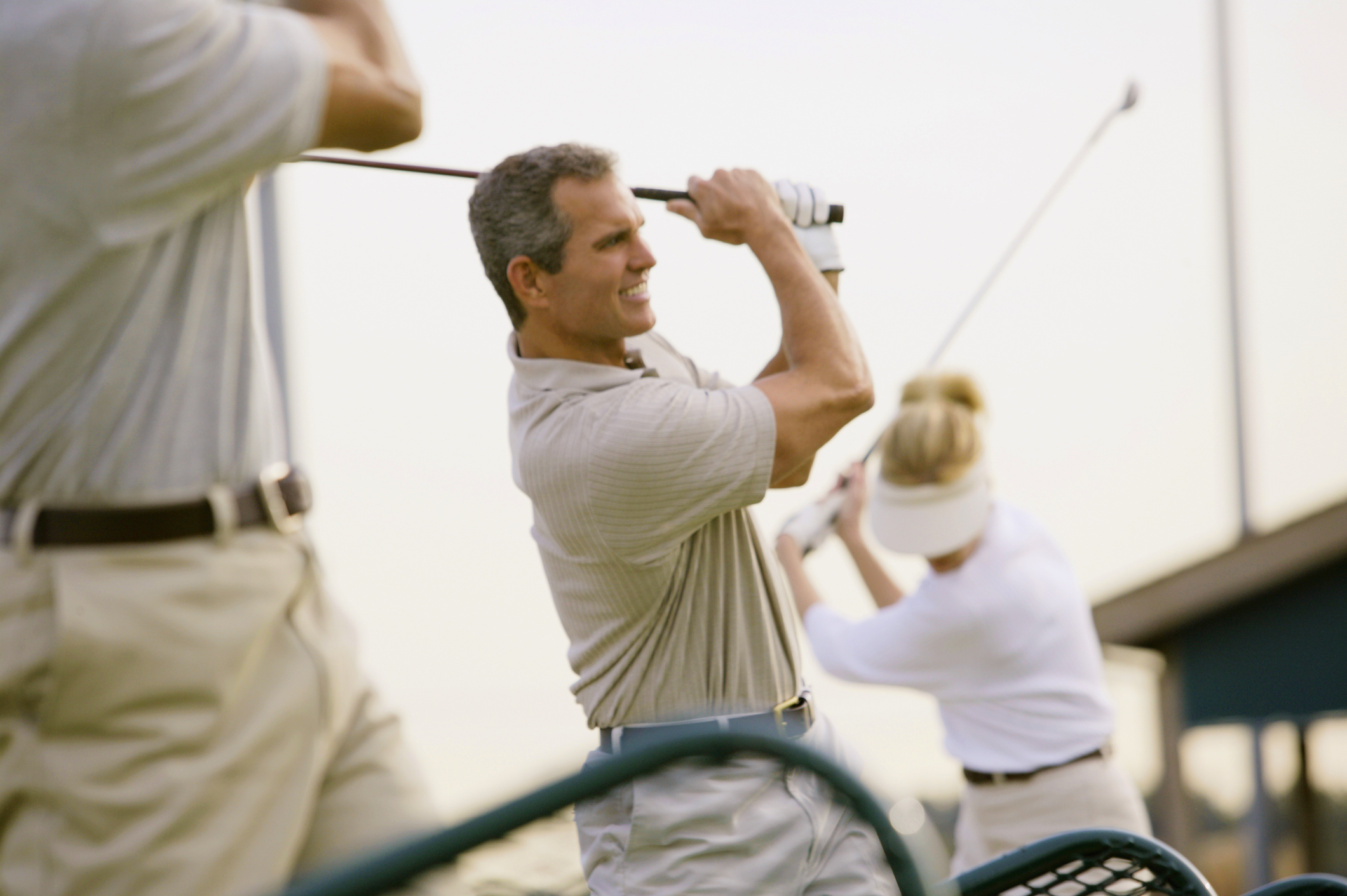 A group of people on a driving range practicing their golf swing